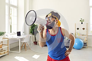 Funny bearded male trainer loudly shouts into a loudspeaker urging everyone to do exercises.