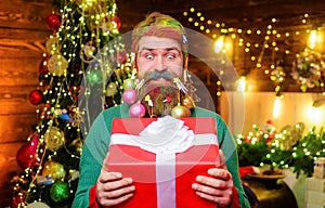 Funny bearded man with Christmas gift box. Smiling man with decoration balls in his beard with New year present. Bearded