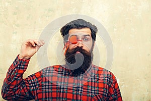 Funny bearded man holding red heart on stick before eye