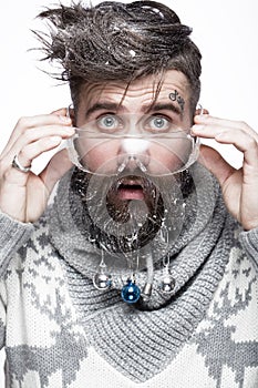 Funny bearded man in a New Year`s image with snow and decorations on his beard. Feast of Christmas.