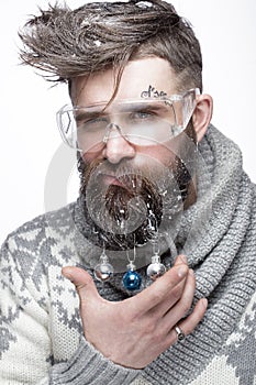 Funny bearded man in a New Year`s image with snow and decorations on his beard. Feast of Christmas.