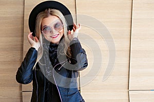 Funny and beautiful blonde in sun glasses and a hat. Trendy girl portrait outdoor. Holds hat