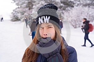 Beauty atractive woman with winter fashion clothing is making funny face in snow skii resort bitting her hand photo