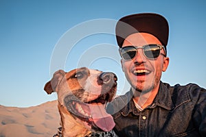 Funny best friends concept: human taking a selfie with dog. Happy young male person makes self portrait with his dog outdoors