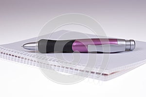 Funny big ballpoint pen on empty notebook