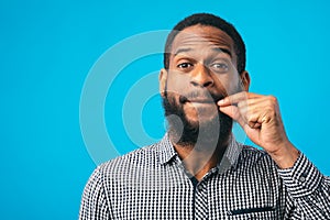 Funny black man making zipping lips gesture with hand
