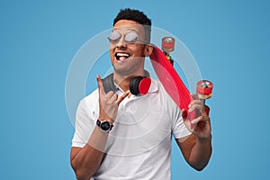 Funny black man with skateboard showing sign of horns