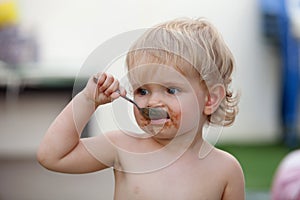 Funny blond baby eating chocolate