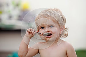 Funny blond baby eating chocolate