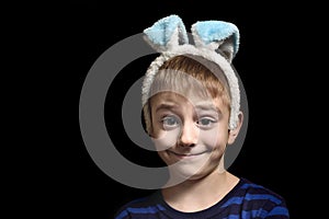 Funny blond boy in ears of ear against a black background. Close-up portrait