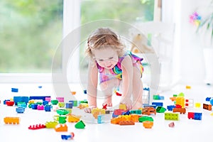 Funny blond toddler girl sitting on floor in mess