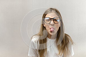 Funny blonde girl in glasses writhing her face, mimicking, having fun. Close-up