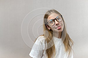 Funny blonde girl in glasses writhing her face, mimicking, having fun. Close-up