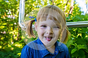 Funny blonde girl in the park. Small pretty female child walking in a summer sunny day