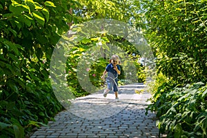 Funny blonde girl in the park. Small pretty female child walking in a summer sunny day