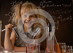 Funny blonde girl with test tubes with colorful substances makes tests at school laboratory