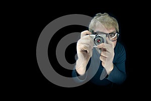 Funny blonde man hold a vintage camera and pointing it at the camera - Isolated on black