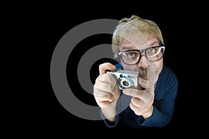 Funny blonde man hold a vintage camera and pointing it at the camera - Isolated on black