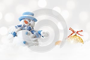 Funny blue snowman on xmas lights bokeh background, white snowflakes, merry Christmas and happy new year card concept