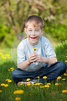 Funny boy with dandelions in a green park. summer