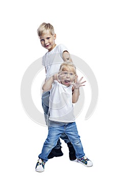 Funny boy and girl. Little brother and sister in white T-shirts and jeans stand and laugh. Love and tenderness in the family.