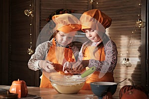 Funny boy and girl in orange chef costumes prepare pumpkin pie