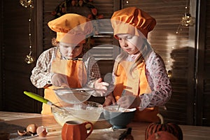 Funny boy and girl in orange chef costumes prepare pumpkin pie
