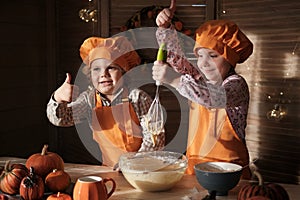 Funny boy and girl in orange chef costumes prepare pumpkin pie