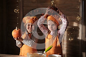 Funny boy and girl in orange chef costumes prepare pumpkin pie