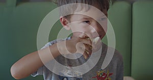 Funny boy in grey t-shirt chews bread Focaccia snack in cafe