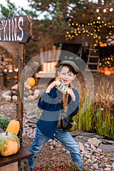 A funny boy in a hat is happy with the money he earned from selling pumpkins