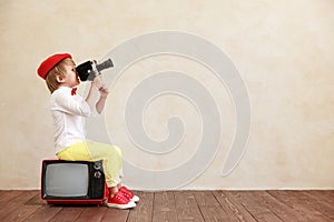 Funny boy holding vintage camera against grunge wall background