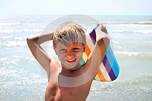 Funny boy joking with kickboard on seashore