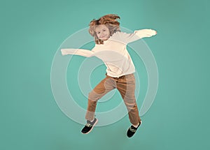 Funny boy jumping in air. Energetic kid boy jumping and raising hands up. Full length body size photo of jumping high