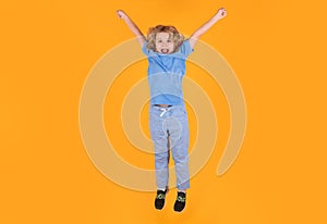 Funny boy jumping. Kid boy 8-9 years old in t-shirt jump isolated on yellow background. Childhood lifestyle concept