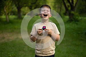 Funny Boy Laughing in the Sunny Field in the Park. Child Takes Colorful Spinner for a Walk. Forest Background.