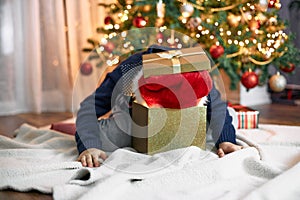 Funny boy in a santa claus hat stuck his head in a gift box. Funny kids. New Year's and Christmas