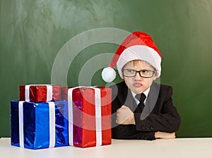 Funny boy in Santa red hat near gifts