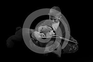 Funny boy with a teddy bear reading a book for bed time in artistic conversion