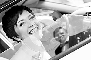 Funny bride in the car smiling groom. Woman 35 years. Wedding