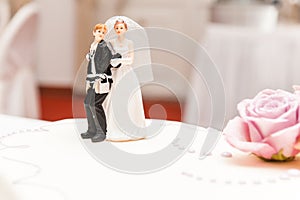Funny bride and groom made of sugar on top of wedding cake