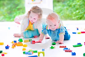 Funny brother and sister playing with colorful blocks