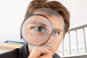 Funny business man holding magnifying glass photo