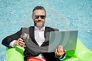 Funny business man in a business suit floating in the water in the pool. Remote summer work online. Crazy freelancer