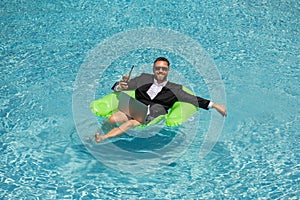 Funny business man in a business suit floating in the water in the pool. Remote work. Crazy freelancer. Business and