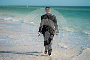 Funny business man in suit on sea. Rear view of back business man in suit in sea water at beach. Business man remote on