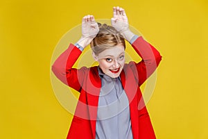 Funny business woman in red suit showing rabbit sign.