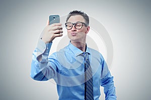 Funny businessman photographing himself on a smartphone