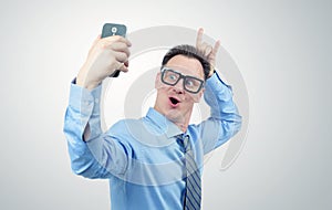 Funny businessman photographing himself on a smartphone