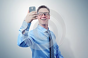 Funny businessman photographing himself on a smartphone